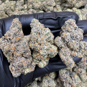 E85 strain cannabis flower featuring dense, frosty buds with deep green and purple hues.