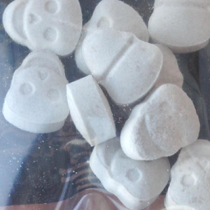 A powerful, white skull-shaped MDMA pill, representing potency and purity, set against a clean background.